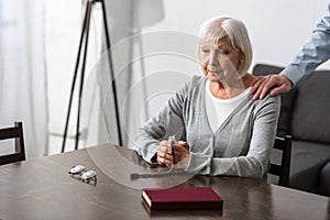 View of man supporting senior mother with wooden rosary