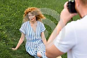 partial view of man taking picture of smiling redhead woman