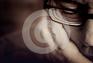 Partial view of a men`s face with glasses and supporting hand
