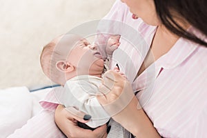Partial view of mother calming down little crying baby