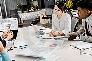 Partial view of multiethnic businesspeople having discussion during meeting