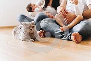 partial view of parents with two sons and grey british shorthair cat sitting on floor