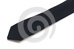 Partial view of a single all black neck tie against a white backdrop