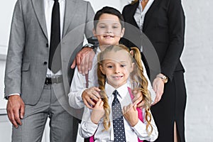 partial view of smiling kids in school uniform and parents in suits