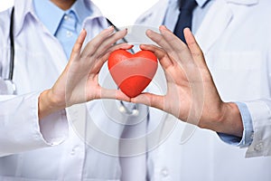 partial view of two doctors holding red heart in hands