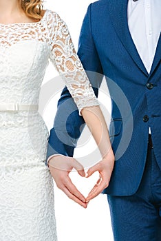 Partial view of wedding couple showing heart symbol made of hands together