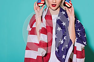 partial view of woman with american flag and cupcakes on blue backdrop celebrating 4th