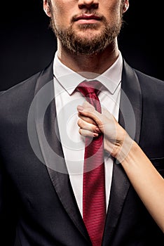 Partial view of woman holding businessman by tie