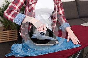 partial view of woman ironing clothes