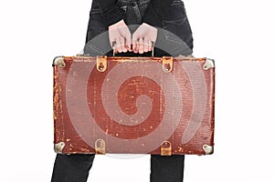 Partial view of woman in jeans holding vintage leather suitcase isolated on white.