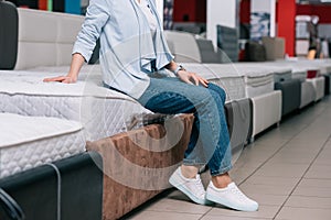 partial view of woman sitting on mattress