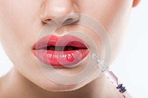 partial view of woman with syringe making beauty injection in lips