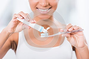 Partial view of young woman putting toothpaste photo