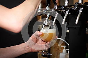 Partially blurred hand pouring beer from silvery bar tap in a pub
