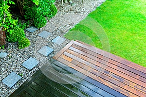 Partially cleaned wooden terrace with a pressure washer by the green lawn photo