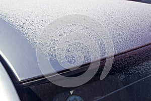Partially covered with frost car roof and windscreen. winter pattern at the sun