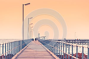 Partially defocused view of Moonta Bay jetty with people at dusk