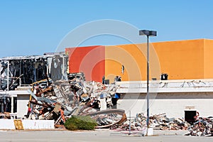 Partially demolished commercial business structure with collapsed wall. Pile of demolition construction debris is ready for haul