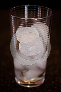 Partially melted ice cubes in a glass with a dark background photo