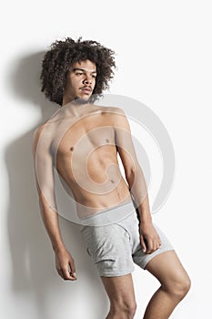 Partially nude young man with curly hair posing over white background