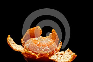 Partially peeled tangerine on a black background with blank space