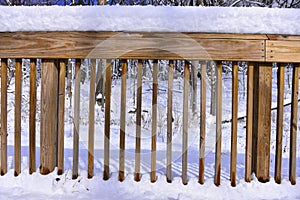 Partially shaded wooden guardrail covered with snow