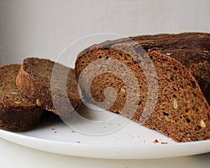 Partially sliced rye grain bread on a white plate