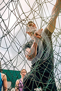 Participant in obstacle course climbing net