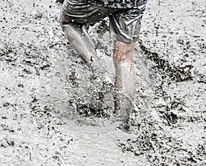 A participant of a physically demanding run is sprinting through the mud