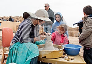 Participants of festival teaches girl to make pitcher of clay