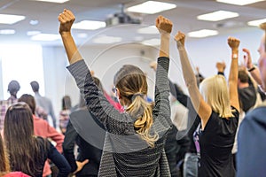 Participants of interactive motivational speech feeling empowered and motivated, hands raised high in the air.