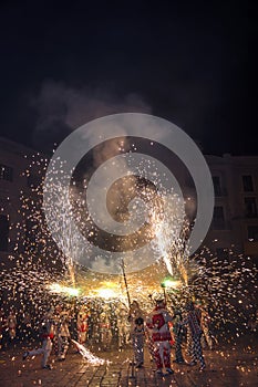 Participants of traditional spectacle Correfocs (fire runs) with lighting fireworks. photo