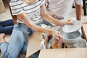 Particle view of couple in their new apartments unpacks their plates from boxes