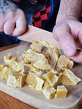 Parting raw beeswax pieces with knife.