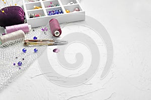 Partitioned box with sewing accessories and threads on white textured background