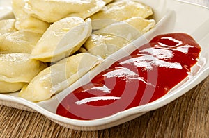 Partitioned dish with dumplings and ketchup on table