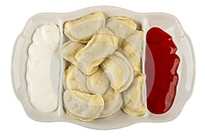 Partitioned dish with dumplings, sour cream and ketchup isolated on white. Top view