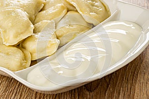 Partitioned dish with dumplings and sour cream on table