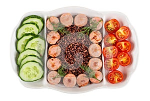 Partitioned dish with fried sausages, red rice, cucumbers, tomato isolated on white. Top view