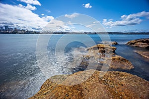 Sydney Harbour with nice rocks in the foreground the soft waves crashing on the shore NSW Australia