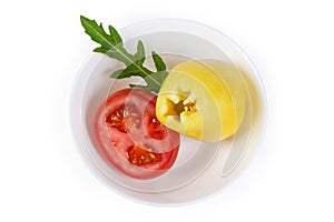Partly cut yellow bell pepper cut and tomato in bowl