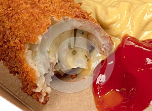 Partly eaten brown crusty dutch kroket with mustard and ketchup isolated