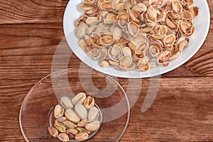 Partly peeled pistachio nuts on saucer and separately empty shells photo