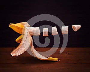 A partly peeled and sliced banana is levatating floating in the air - wooden background