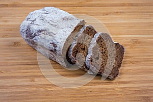 Partly sliced brown bread on a wooden cutting board