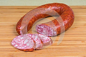 Partly sliced pork bologna sausage on a wooden cutting board