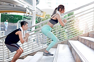 Partner buddy runner sport man and woman in athletic workout clothes jump up the stairs, exercise climbing staircase outside