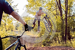 Partner cyclist, looks like performs jumps and stunts with a bike. in the forest against the setting sun