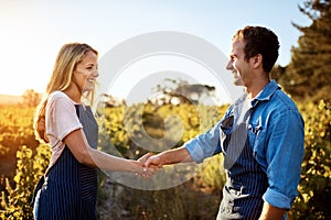 Partnering up to bring quality produce. a handsome young man and an attractive woman shaking hands on a farm.