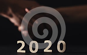 Partners shaking hands on the background in new 2020 year, wooden figures of date on a black background, concept of business and